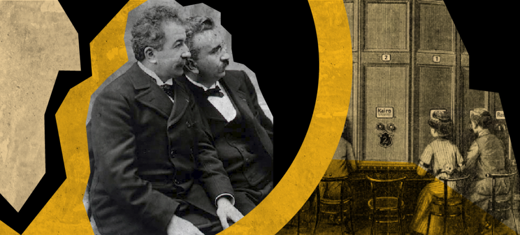 two men sitting next to each other and women looking through early cinema