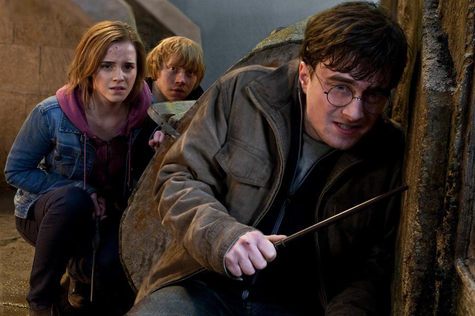 Man with glasses and wand hiding with a woman and another man