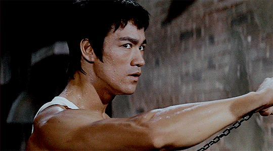 man with white tank top holding weapon